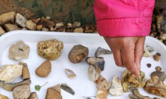 child's hand and gravel on a white tray